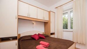 A bedroom with a bed, a wardrobe, and a window with curtains. - Apartments and Room Thea (Zadar)