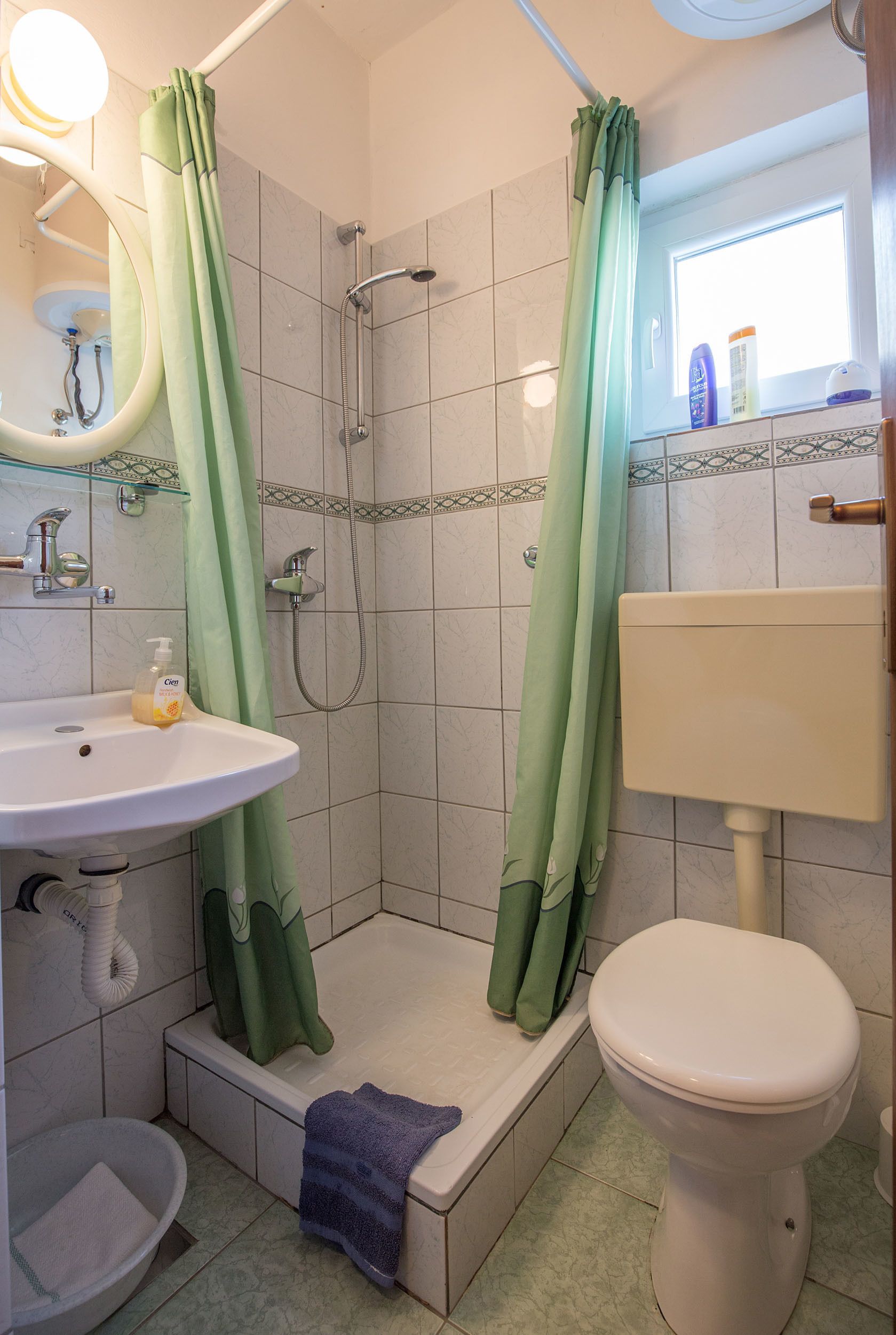 Kylpyhuone, jossa on suihku, wc, pesuallas ja ikkuna.