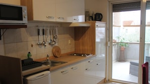 A kitchen with white cabinets, a microwave, a sink, and a wooden countertop. - Apartments and Room Thea (Zadar)