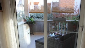 A balcony with wicker furniture, potted plants, and a view of a garden. - Apartments and Room Thea (Zadar)