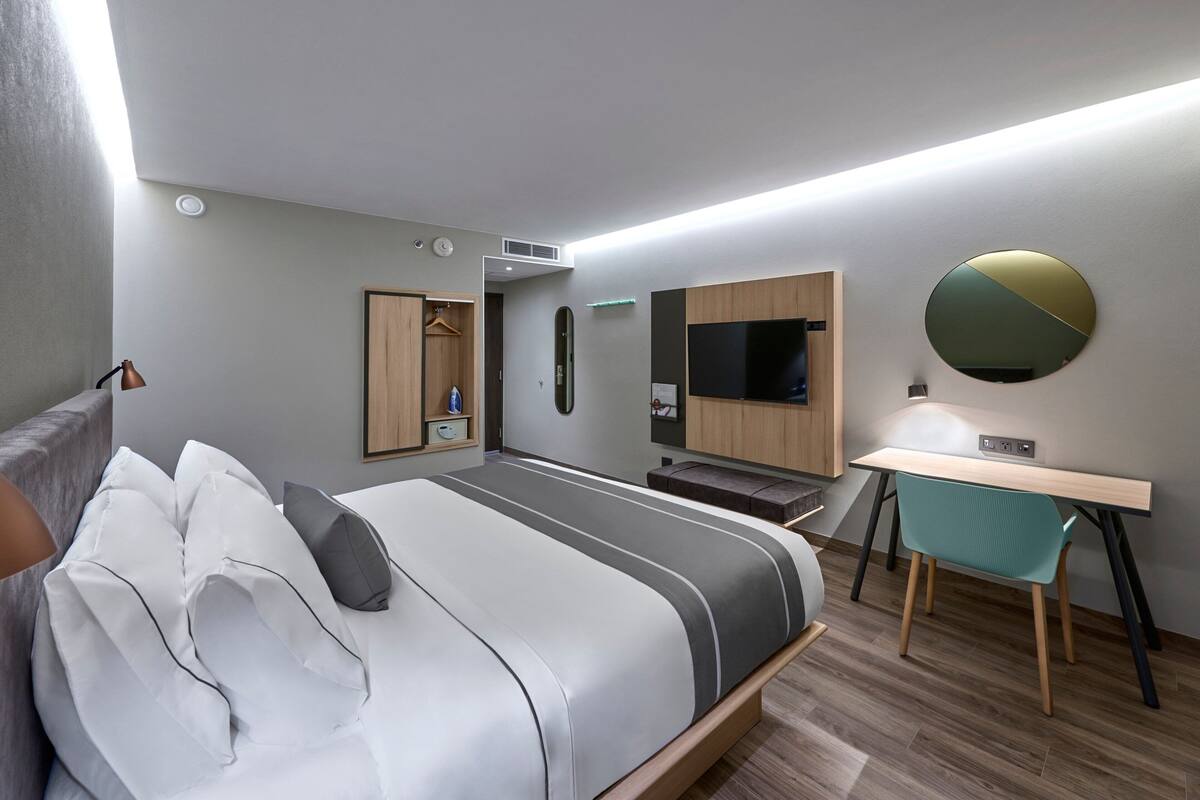 Ein modernes Hotelzimmer mit Bett, Schreibtisch und Fernseher.