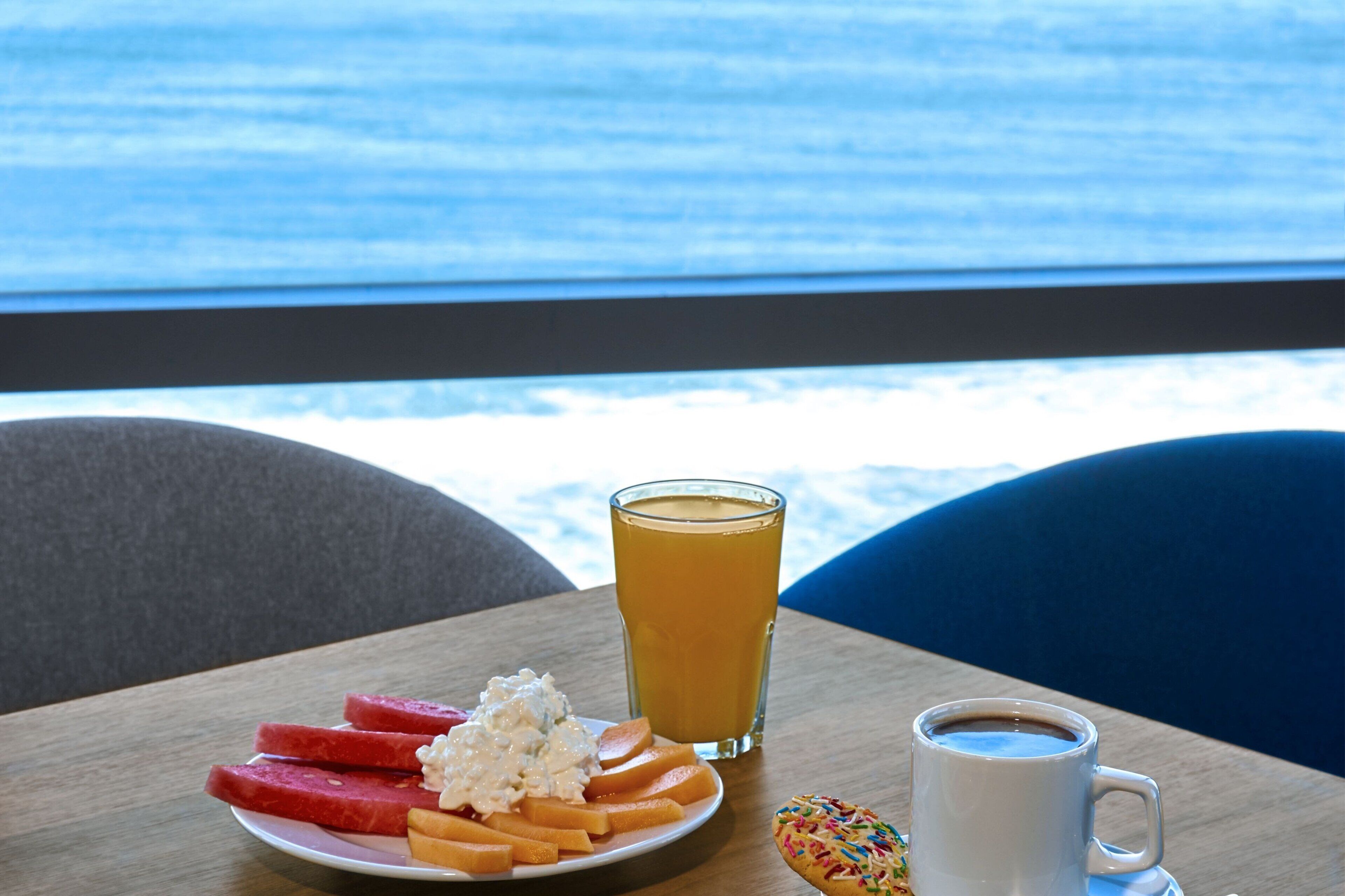 A table with a plate of food, a glass of orange juice, and a cup of coffee.
