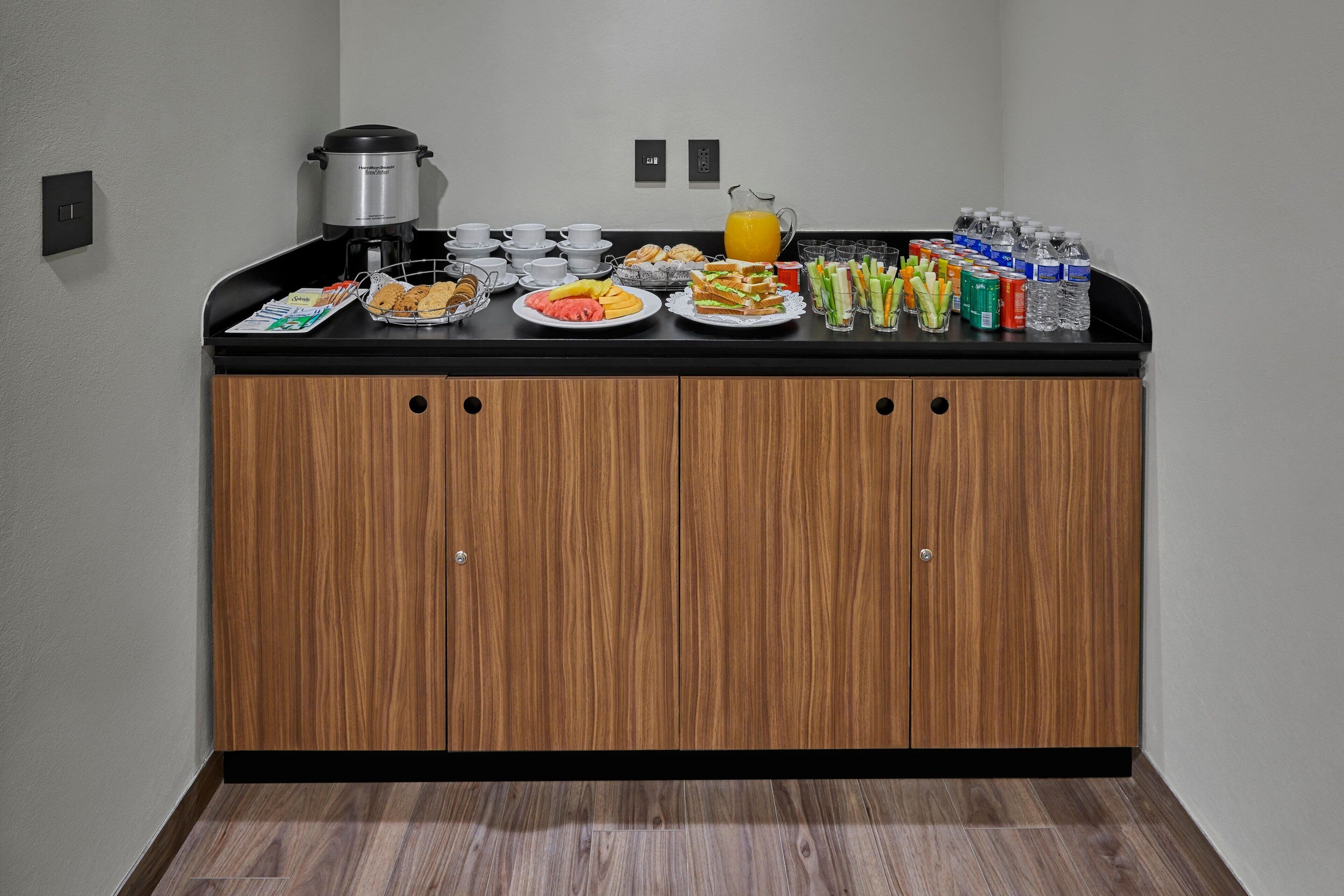 A breakfast buffet with a coffee maker, juice, and various food items.