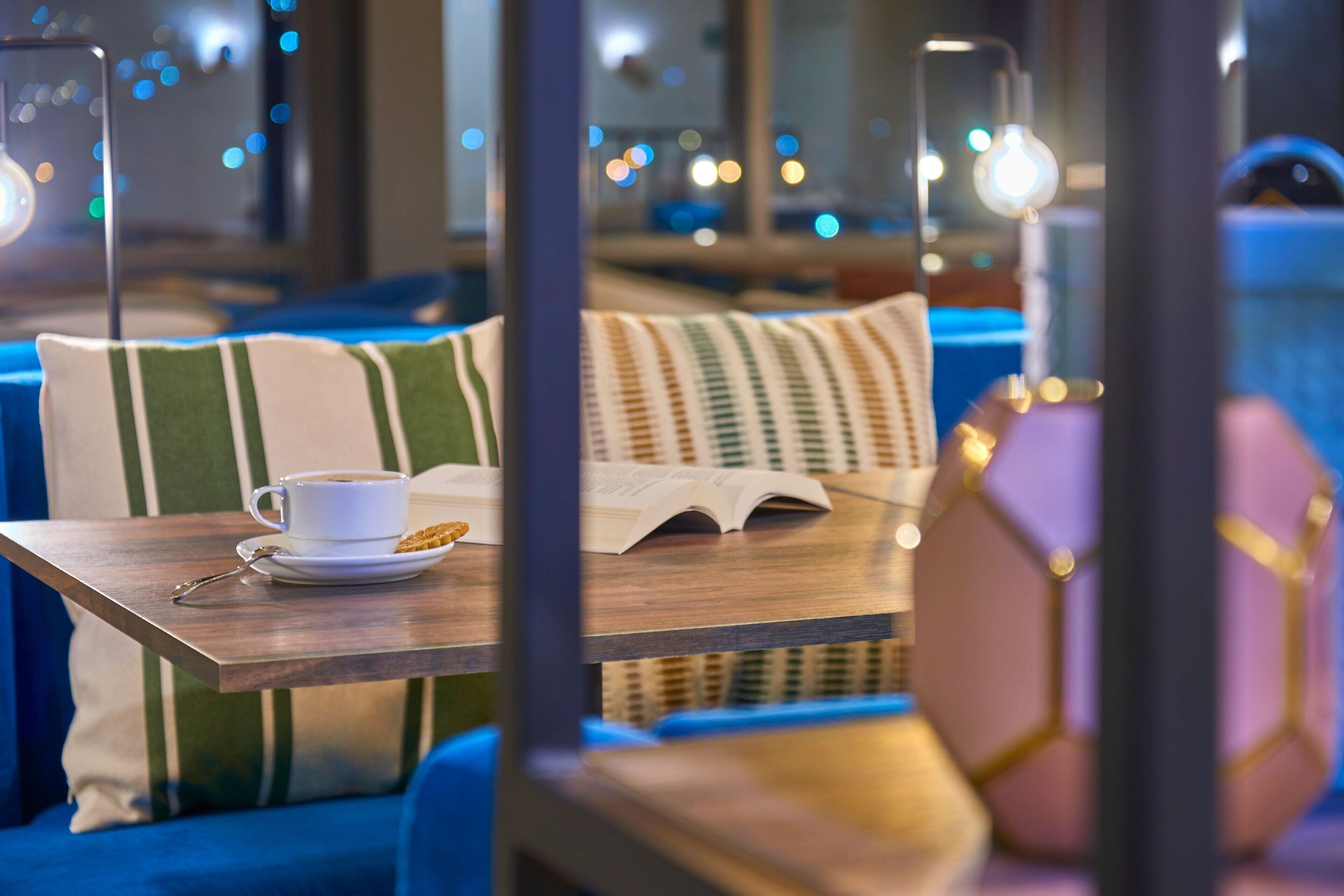 A cozy seating area with a table, a cup, and an open book.