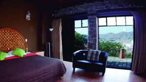 Un dormitorio con cama, una silla y vistas al exterior.