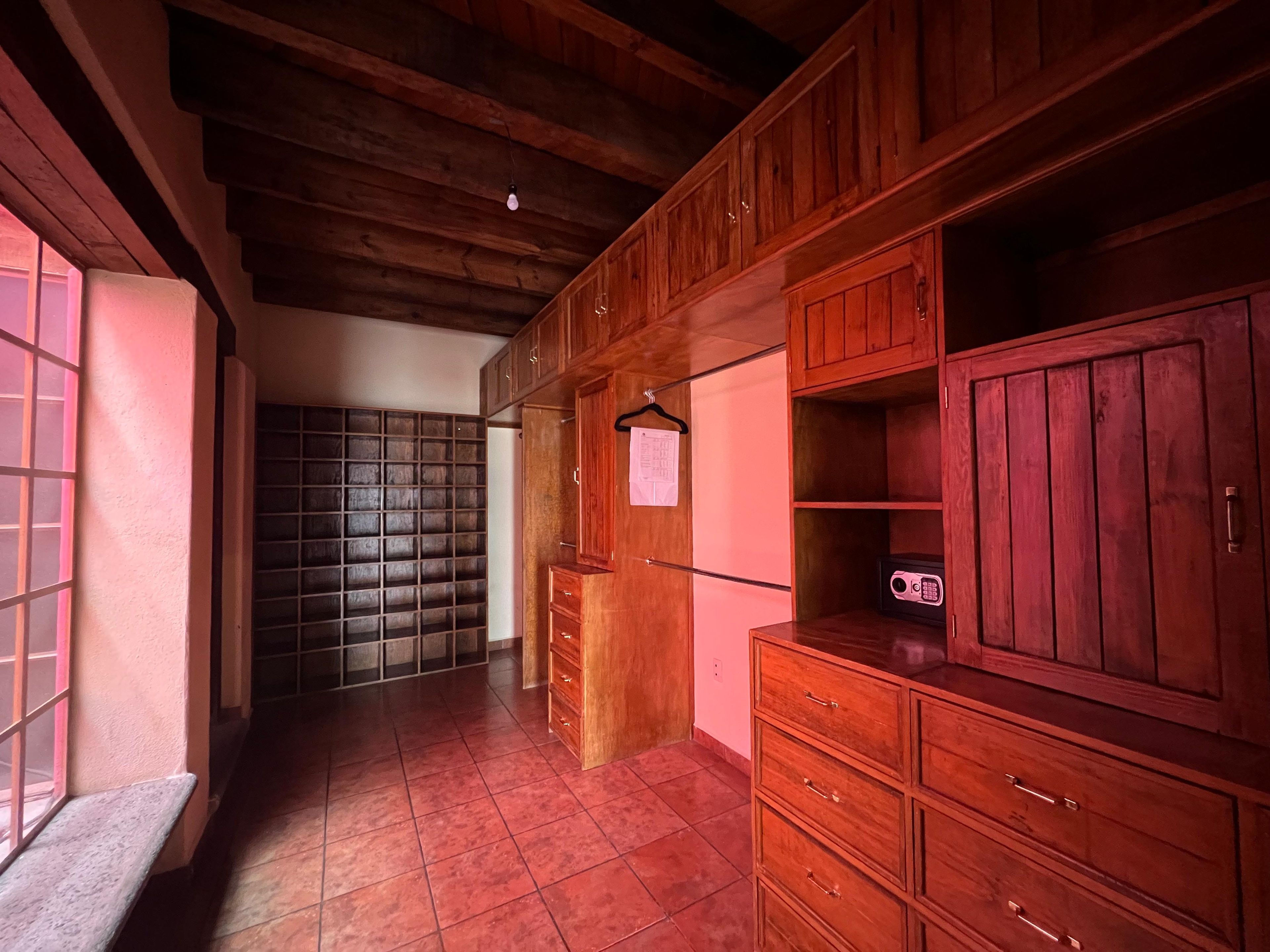 Um corredor com armários de madeira, piso ladrilhado e um banco.