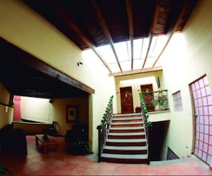 Un amplio salón con una escalera que lleva a una puerta, un sofá y una mesa de centro.