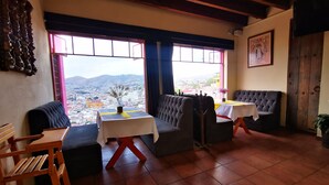 Habitación acogedora con vistas a un paisaje urbano, que incluye un sofá, dos mesas y una silla de madera.