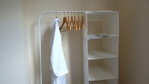 Un porte-vêtements en métal blanc, muni de cintres en bois, sur lequel est suspendue une serviette blanche.
