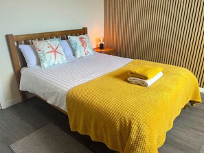 A bed with a white mattress, a yellow blanket, and decorative pillows. - Beach & City Access Flat 2 Floors, Full Kitchen near train 7mins (Methil)