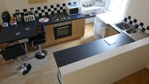 Une cuisine de taille réduite équipée d’une cuisinière à gaz, d’un grille-pain et d’un évier.