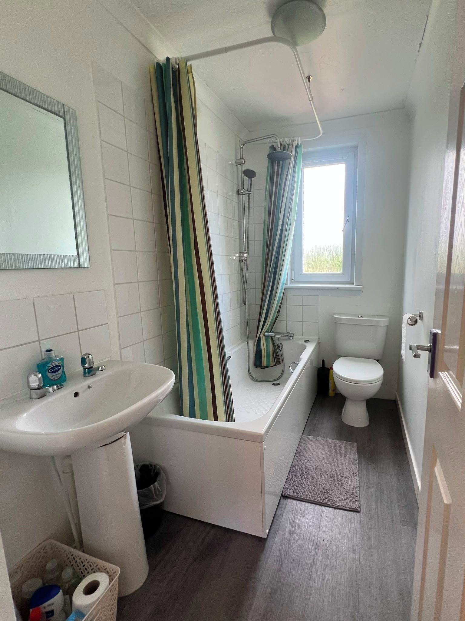 A bathroom with a sink, toilet, bathtub, and shower curtain.