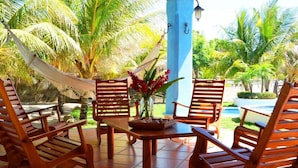 A wooden outdoor seating area with a table and chairs, surrounded by palm trees and a hammock. - Exclusive Beachfront Large Spanish Estate for up to 30 people, WiFi (Pochomil, San Rafael del Sur)