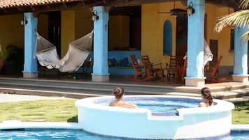 Relax by the tranquil pool surrounded by lush greenery and comfortable seating.
