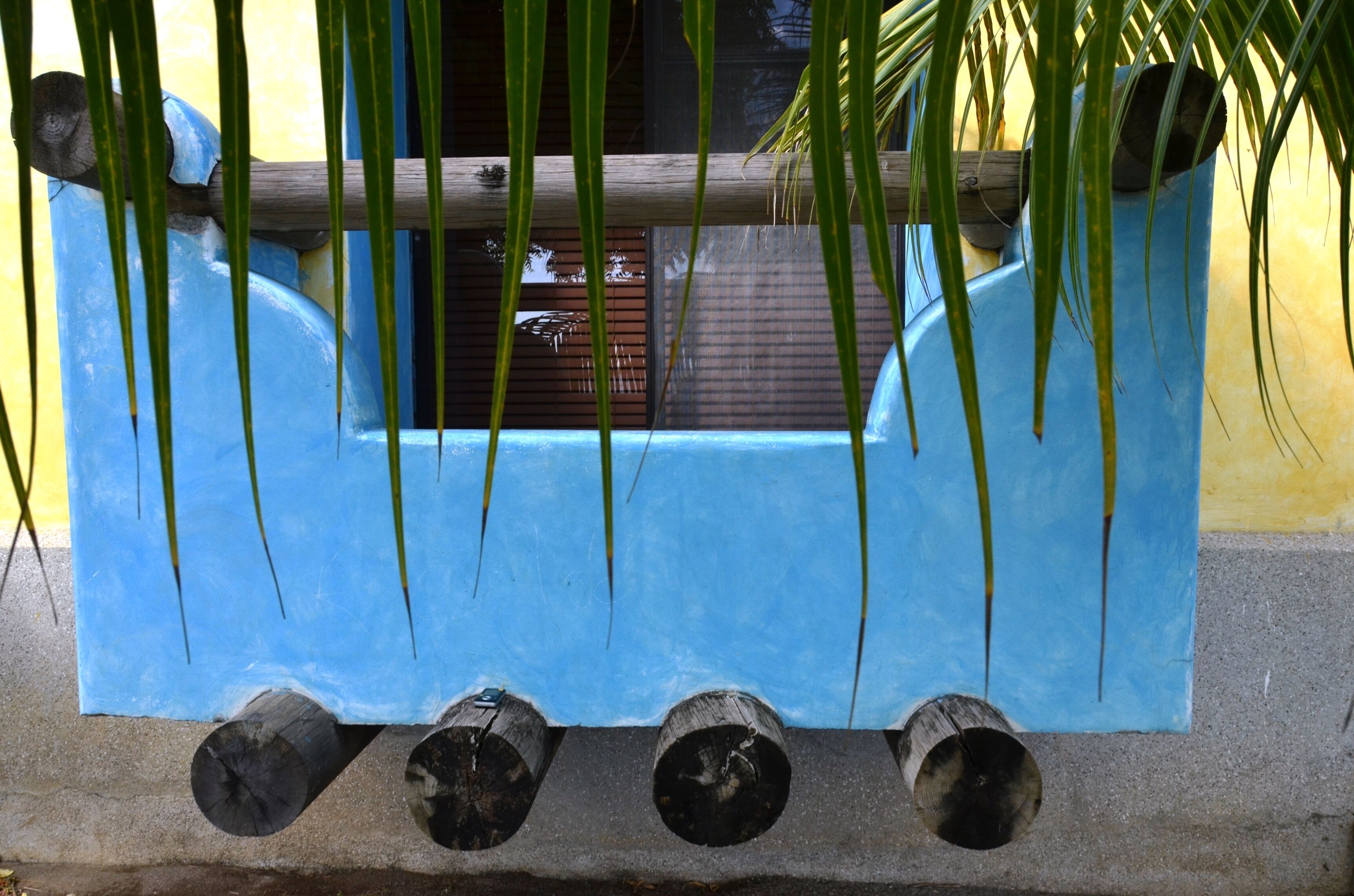 A blue water feature with logs and a window in the background.
