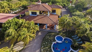 A two-story house with a tiled roof, surrounded by lush greenery and palm trees. - Exclusive Beachfront Large Spanish Estate for up to 30 people, WiFi (Pochomil, San Rafael del Sur)