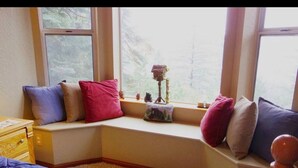 A cozy room with a built-in bench along a window, a wooden dresser, and a colorful quilt on the floor. - Lovely Cabin with lake views (Lake Arrowhead)