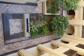 Experience the stylish lobby with a geometric patterned floor, lush greenery, and a seating area with comfortable chairs and tables.