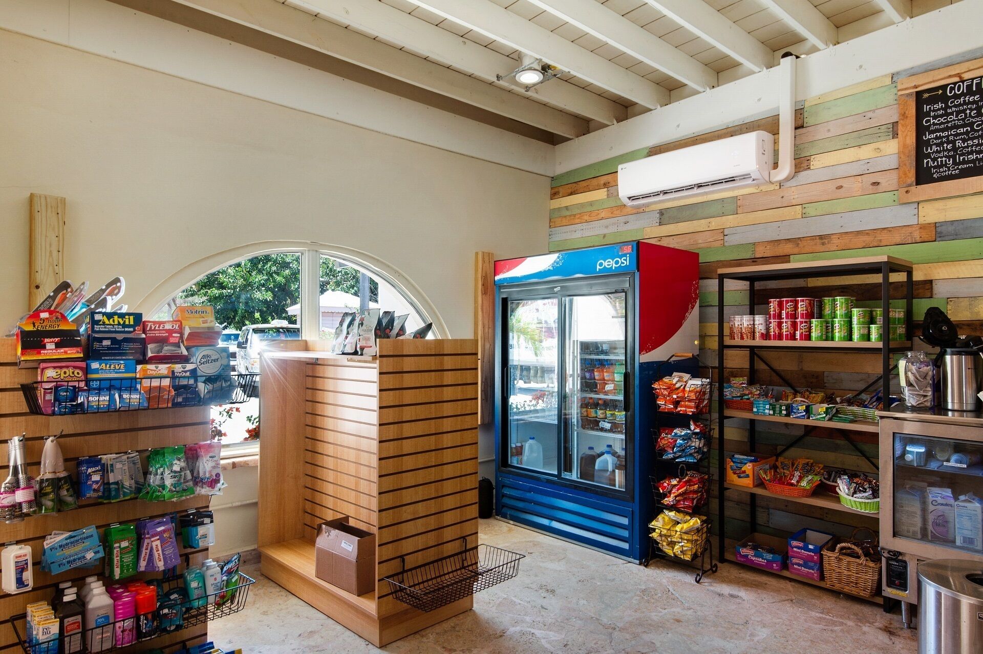 Een kleine buurtwinkel met diverse producten op de planken, een koelkast voor Pepsi en een airconditioner aan de muur.
