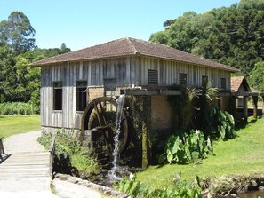 Un edificio rústico de madera con una gran noria de agua y cimientos de ladrillo.