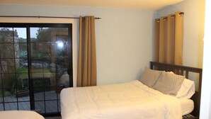 A bedroom with a bed, a window with curtains, and a view of the outside.
