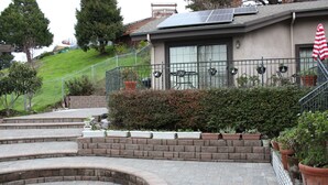 A residential property with a landscaped garden, a curved brick pathway, and a solar panel on the roof.