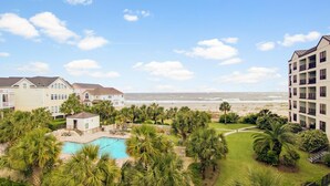 Un complexe hôtelier doté d’une piscine, de palmiers et offrant une vue sur la plage.