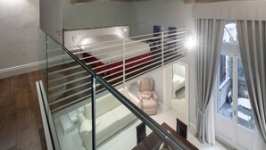 Een modern interieur met een glazen trap, een rode bank en een witte stoel.
