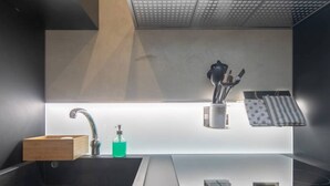 Een moderne badkamer met een zwart wastafel, een houten zeepbakje, een groene zeepdispenser en een handdoekrek met gestreepte handdoeken.