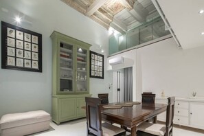 Un comedor con mesa de madera, sillas, un armario verde e ilustraciones botánicas enmarcadas en la pared.