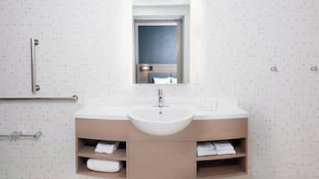A modern bathroom with a large sink, wooden vanity, and a mirror above it.