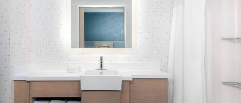 A modern bathroom with a white sink, wooden cabinets, and a mirror above the sink.