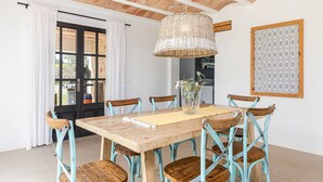 Un comedor con mesa de madera, sillas color turquesa y una lámpara colgante de fibra.