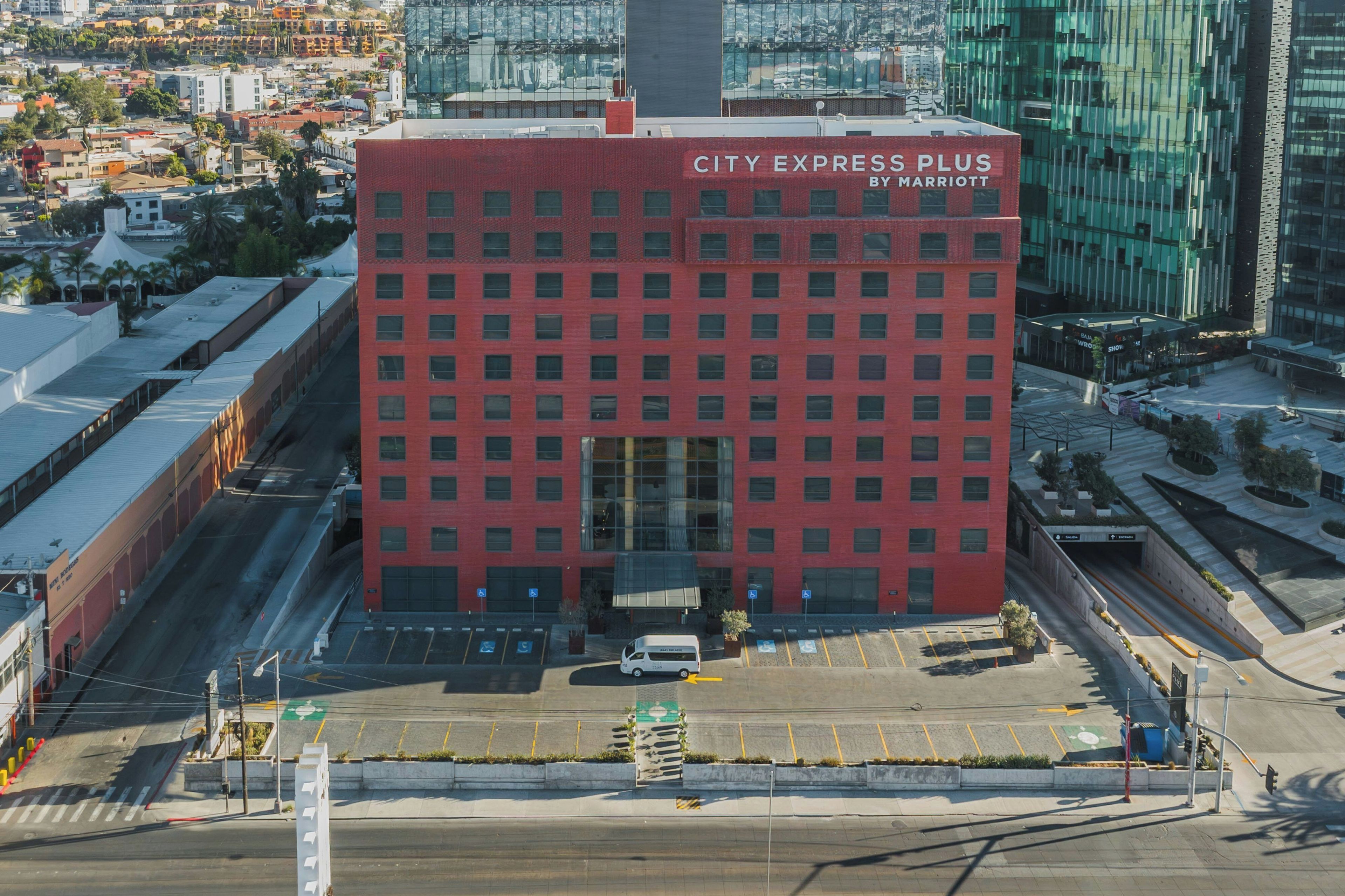 Un edificio rojo con el letrero 'CITY EXPRESS PLUS BY MARRIOTT' en la parte superior.