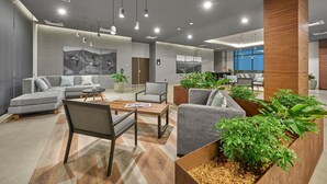 A modern lounge area with sofas, chairs, and a coffee table, featuring a large wooden planter with plants. - City Express Plus by Marriott Tijuana (Tijuana)