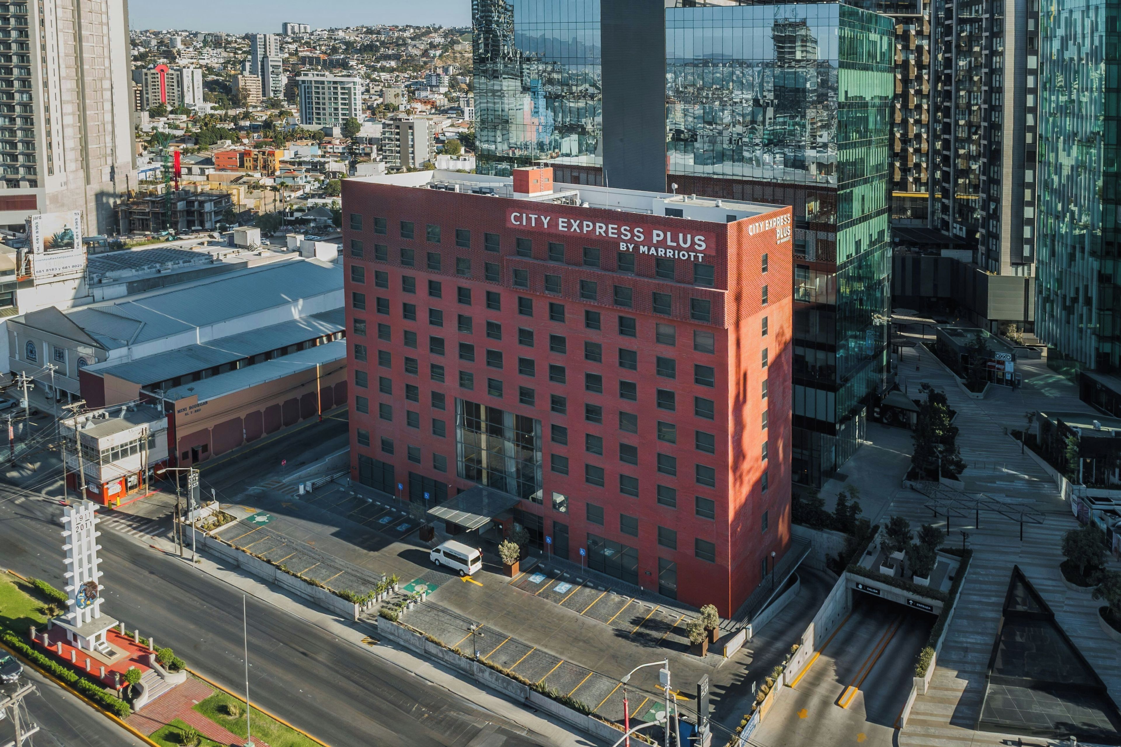 Un hôtel à plusieurs étages, avec une façade rouge, de grandes fenêtres et un parking situé à l’avant.