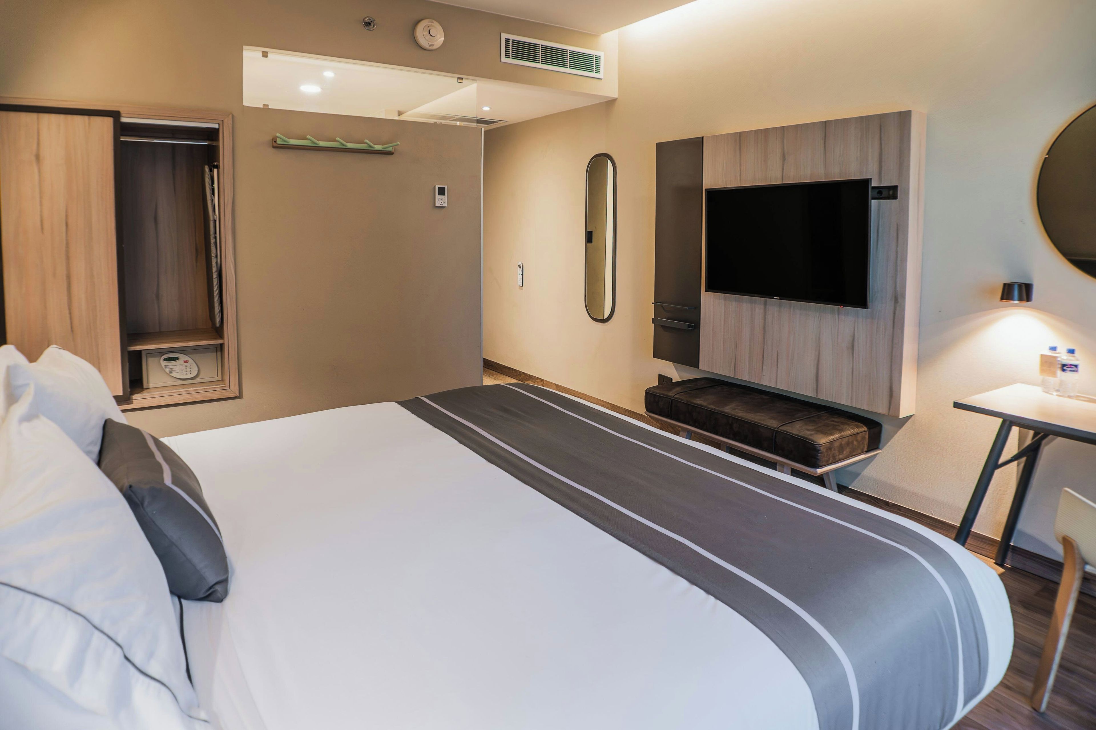 A hotel room with a large bed, a flat-screen TV, a desk, and a seating area.