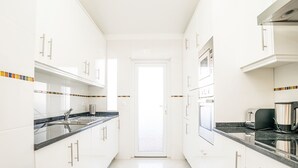 A modern kitchen with white cabinets, black countertops, and a stainless steel range hood. - Jasmine Apartment, AC, Pool, Balcony (Albufeira)