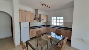 Una cocina moderna con armarios de madera, una mesa de comedor de vidrio y un microondas integrado.