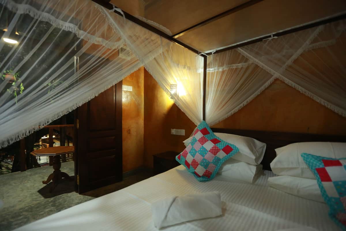 A bed with white linens, a canopy, and a quilted pillow.
