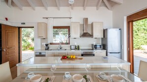 Une cuisine moderne dotée d’un îlot central, de meubles en bois et offrant une vue sur la verdure environnante.