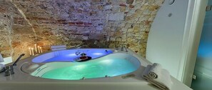 Un bain à remous avec un mur en pierre en arrière-plan.
