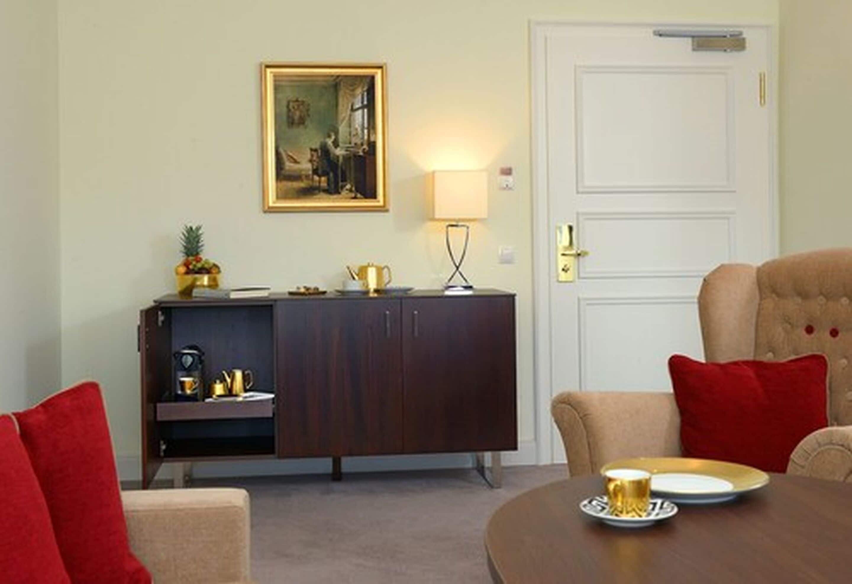 Ein Raum mit einem braunen Esstisch, einem cremefarbenen Sofa, einem dunklen Holzschrank und einer weißen Tür.