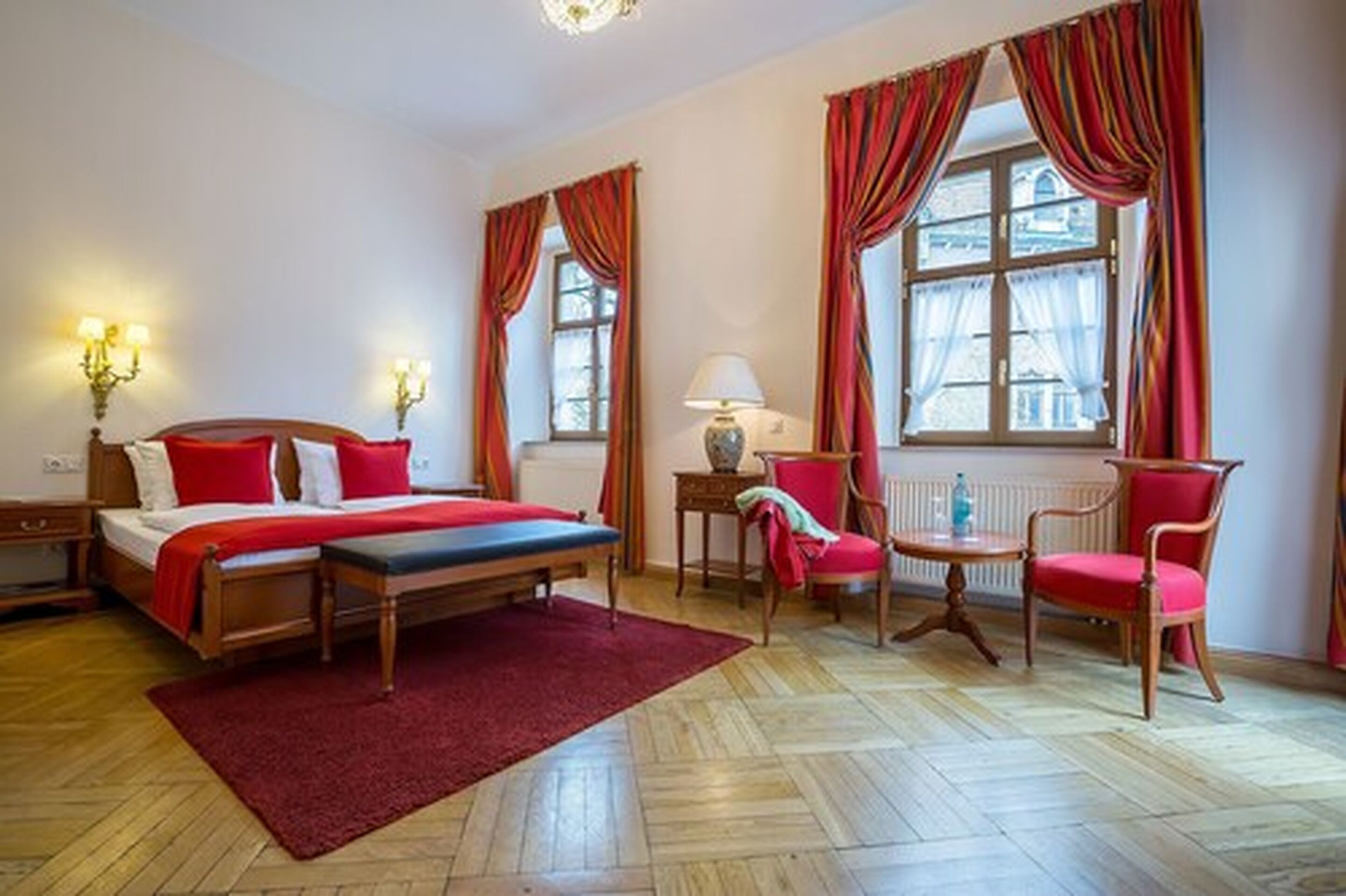Una habitación de hotel con cama, dos sillas, una mesa y ventana con cortinas.