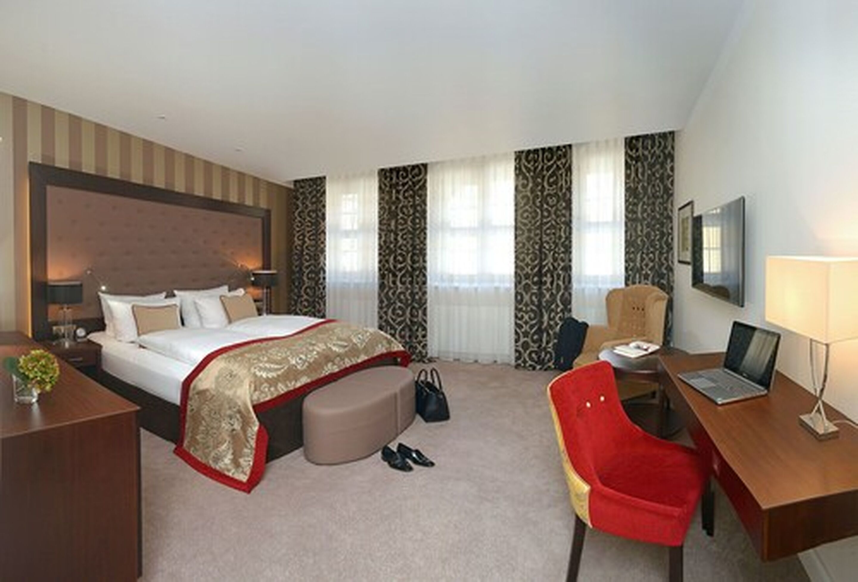 A hotel room with a bed, desk, chair, and a TV.