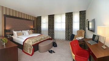 A hotel room with a bed, desk, chair, and a TV.