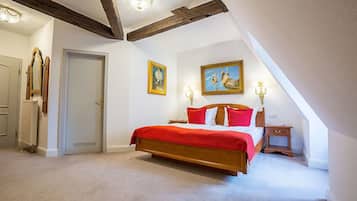 A bedroom with a large bed, a door, and two paintings on the wall.