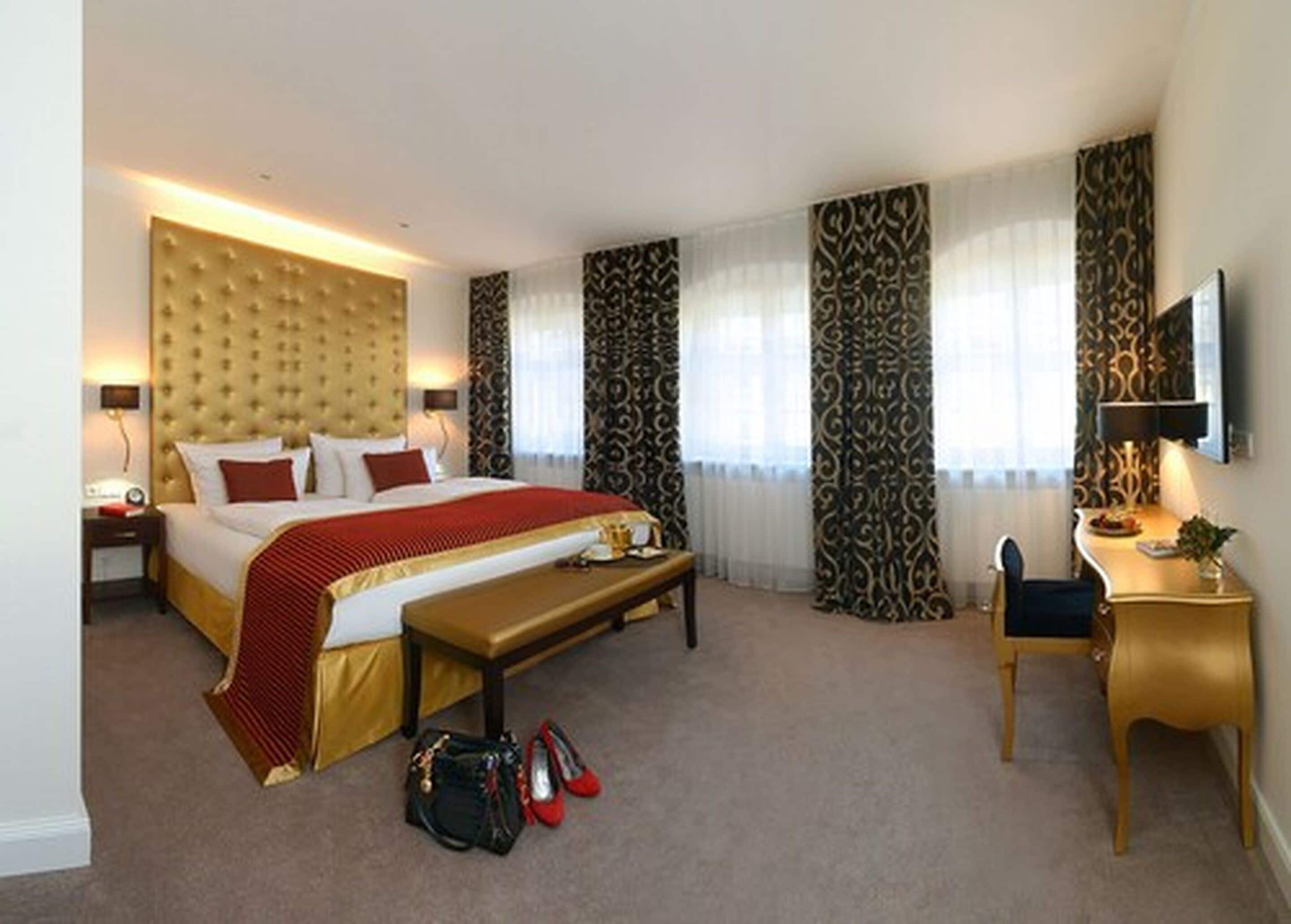 Una habitación de hotel con una cama grande, un escritorio, una silla y un televisor.