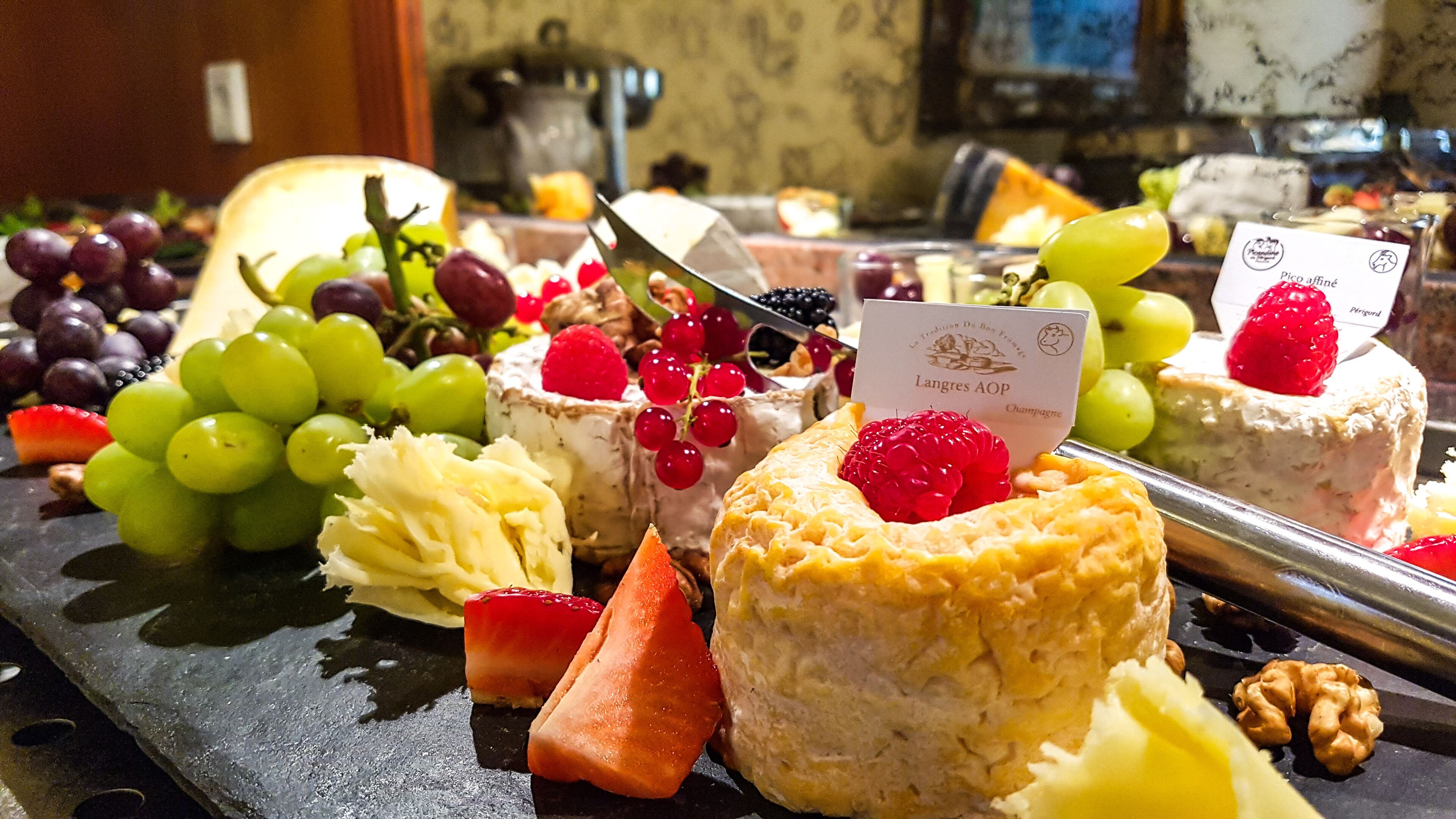 A variety of cheeses, fruits, and pastries on a serving board.