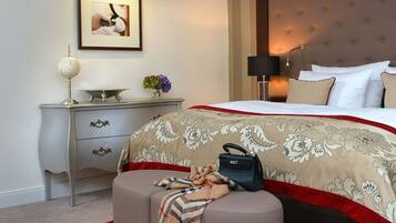 A hotel room with a bed, a nightstand, a lamp, a framed picture, and a small table with a globe and flowers.